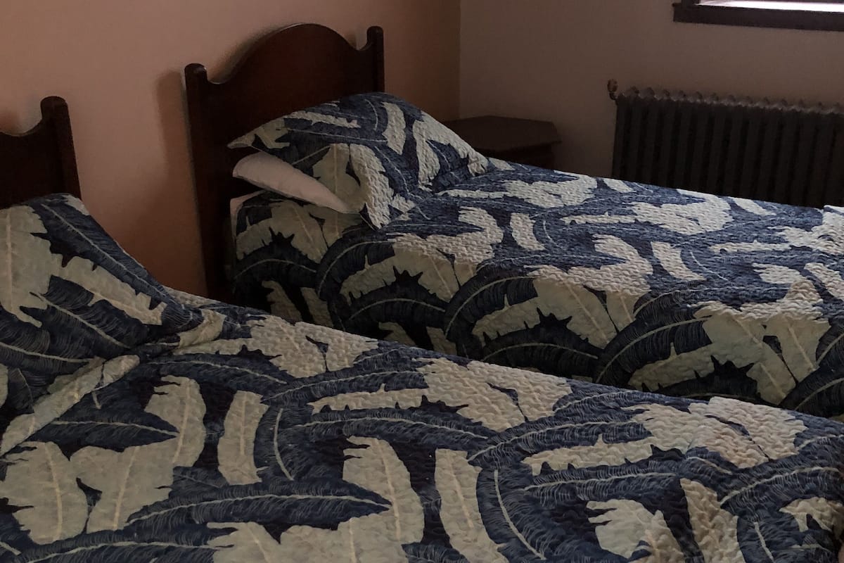 A bedroom with a wooden ceiling and a window. There is a bed with a patterned bedspread.