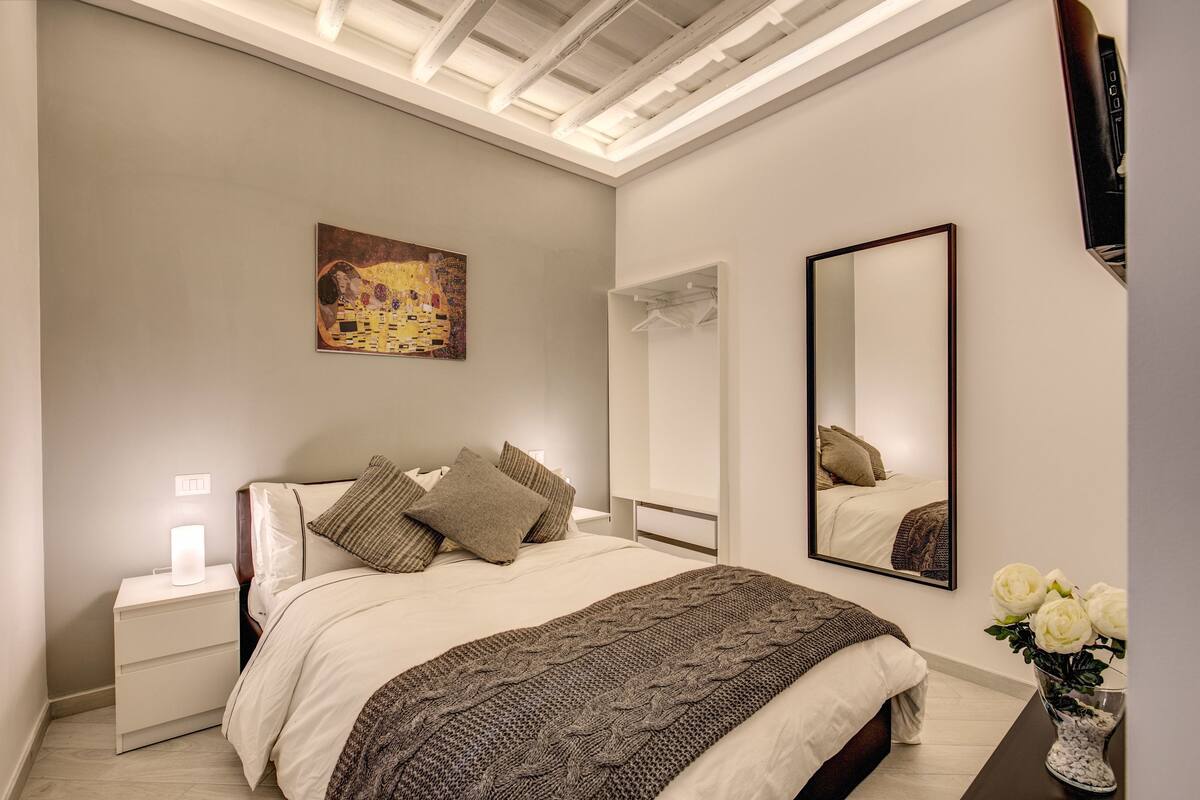 Ein Schlafzimmer mit Bett, Nachttisch, Spiegel und Bildern an der Wand.