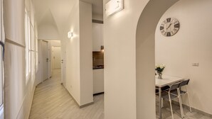 A hallway leading to a dining area with a clock on the wall. - Residenza Costaguti (Rome)