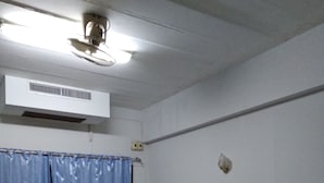 A room with two beds, a ceiling fan, an air conditioning unit, and a window with blue curtains. - Saichonview Resort (Kanchanaburi)
