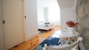 A modern living room with a white sofa, a round white table with a vase of flowers, and a blue patterned rug.