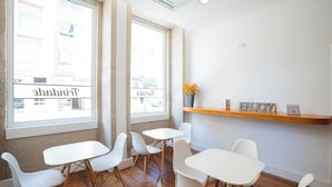A modern interior with white furniture, large windows, and a wooden shelf with decorative items.