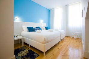 Un dormitorio con una cama grande, una mesita de noche, una pequeña mesa y una ventana con cortinas.
