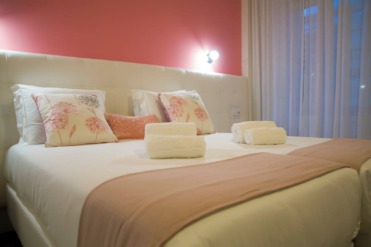 A neatly made bed with floral pillows and a beige bedspread.