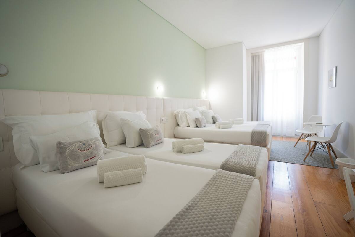 A hotel room with two beds, a small table, and a chair.