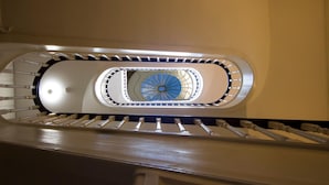 A modern elevator shaft with a circular skylight and a central spiral staircase.