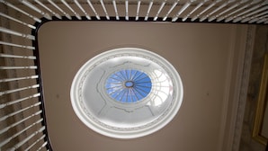 A circular skylight with a blue glass center and white trim, surrounded by a white ceiling with decorative molding.