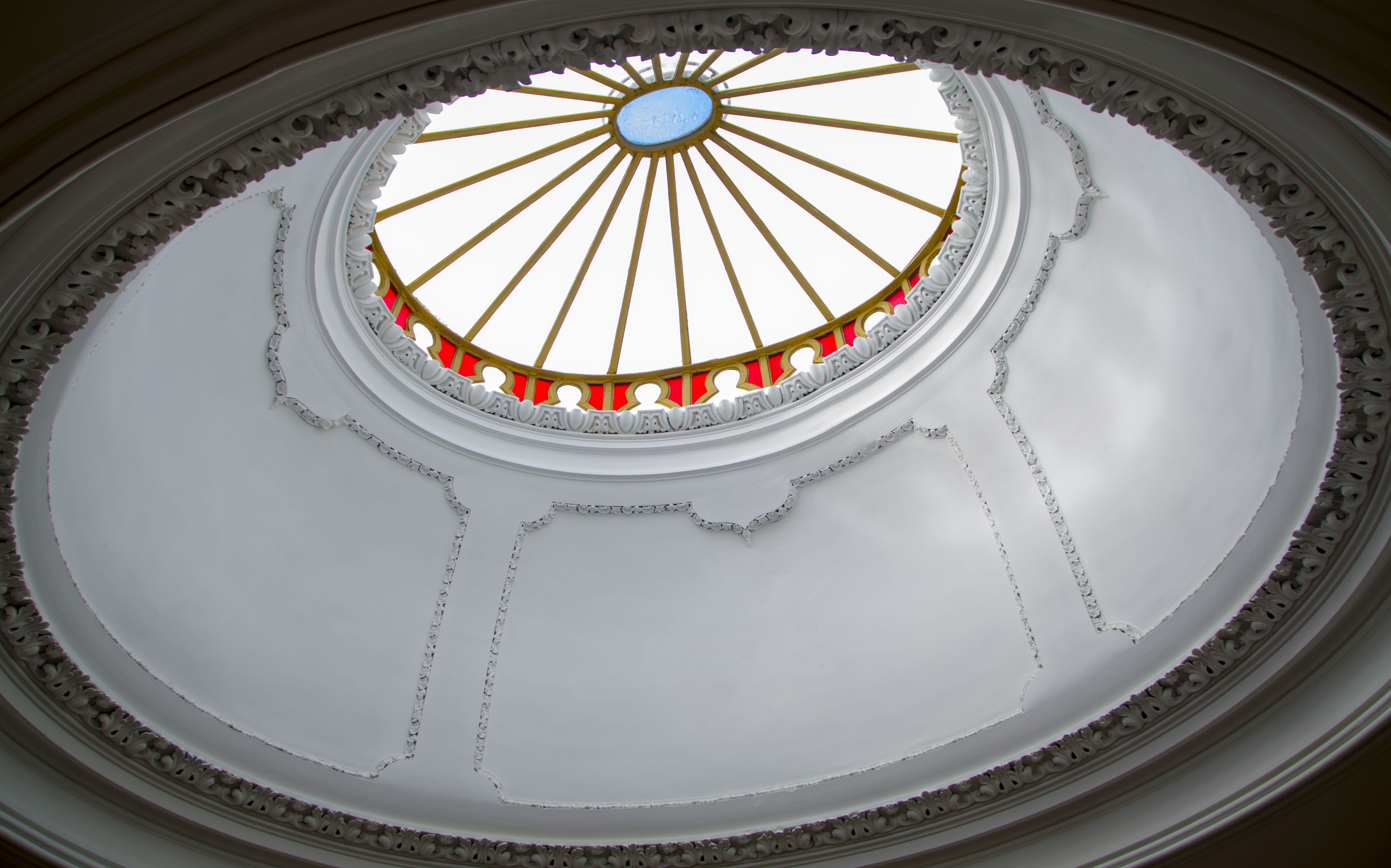A dome with a central oculus, ornate gold and red detailing, and a white interior.