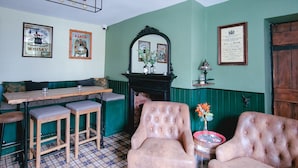 A room with a checkered floor, a fireplace, a mirror, and a bar area with stools. - Red Lion Inn (Wooler)