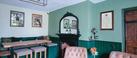 Una habitación con piso a cuadros, chimenea, espejo y un área de bar con taburetes.