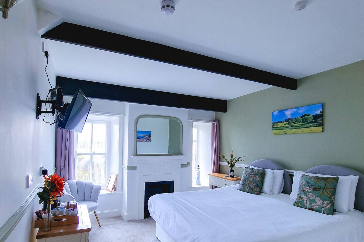 A bedroom with a bed, bedside table, lamp, and a painting on the wall.