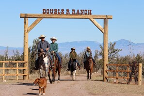 Uma placa de madeira com a inscrição 'DOUBLE R RANCH', indicando um ambiente de fazenda.