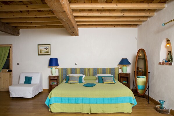 Un dormitorio con cama, una silla, un espejo y una lámpara.