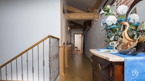 A wooden staircase with a railing, a hallway with wooden flooring, and a dresser with a blue cloth. - Domaine de la Bellière (Villars-les-Dombes)
