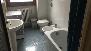 Un baño con lavamanos, inodoro y bañera.