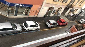 Vista de una calle con coches aparcados, un local con la señalización 'STOSA Cucine' y un edificio con ventanas arqueadas.
