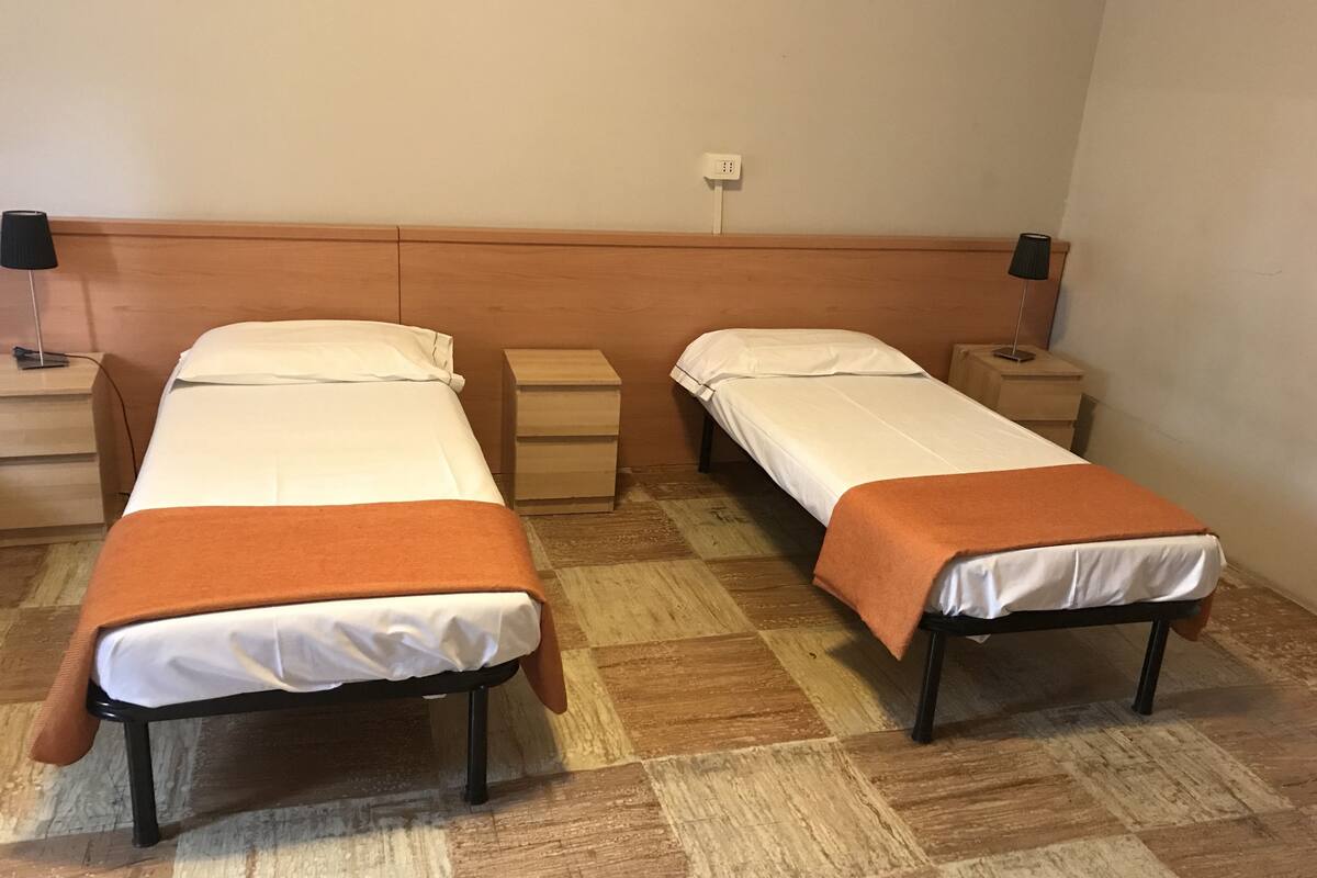 Two single beds with wooden headboards, a bedside table, and a nightstand with a lamp.