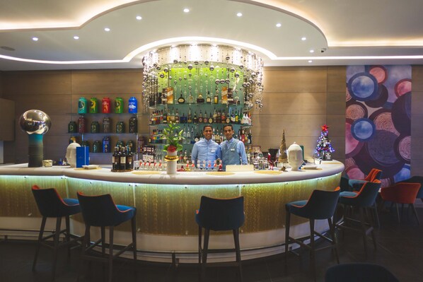 Una zona de bar con una barra circular, varios taburetes y un candelabro decorativo.
