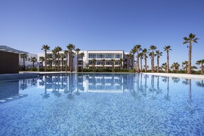 A modern hotel with a swimming pool surrounded by palm trees. - The View Bouznika (El Mansouria)