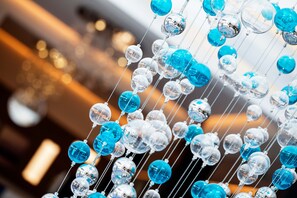 A close-up of a decorative installation with clear and blue glass spheres suspended by thin wires. - The View Bouznika (El Mansouria)