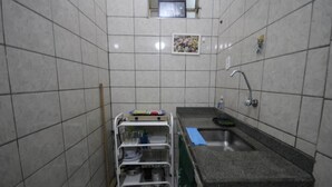 Un baño pequeño, con azulejos, que incluye un lavamanos, un espejo y un estante con artículos de aseo.