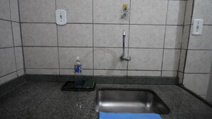 Un baño con lavamanos, grifo, dispensador de jabón y una botella de agua sobre la encimera.
