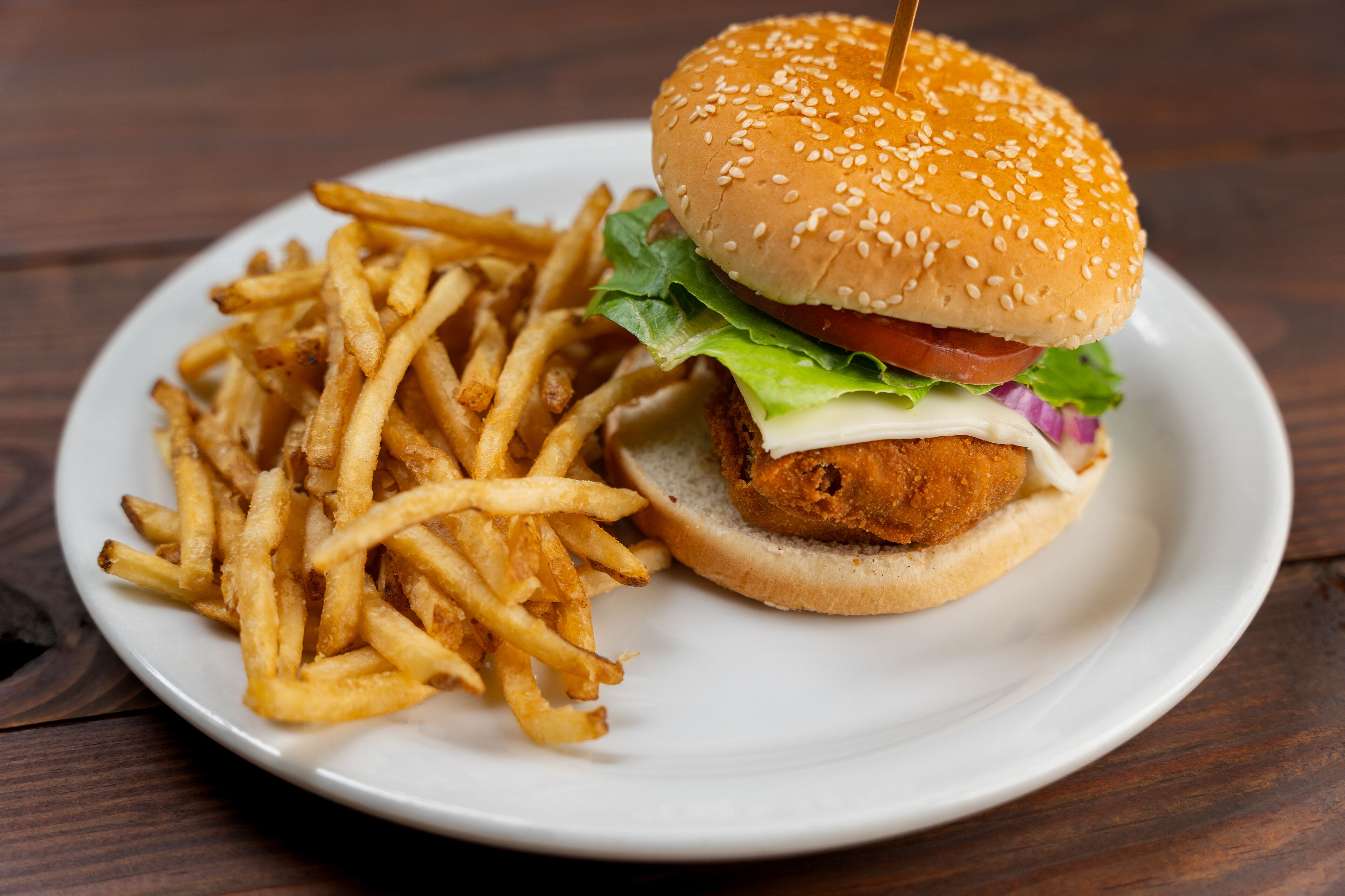 Un plato con una hamburguesa de pollo y papas fritas.