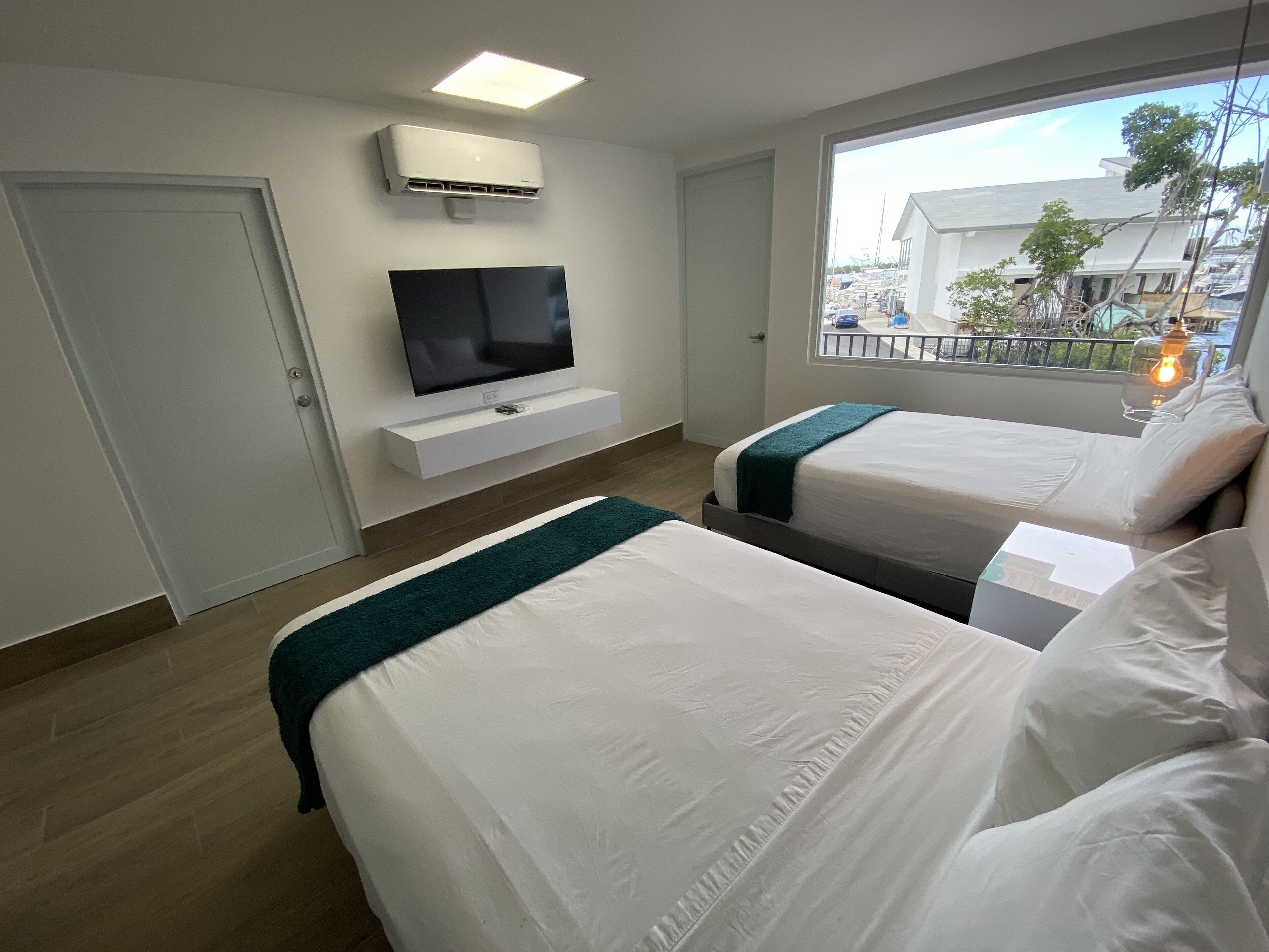 Habitación de hotel con dos camas, televisor, ventana con vista al exterior y aire acondicionado.
