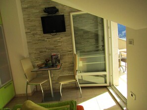 Suite estudio, vista al mar | Área de sala de estar | Televisión de pantalla plana 