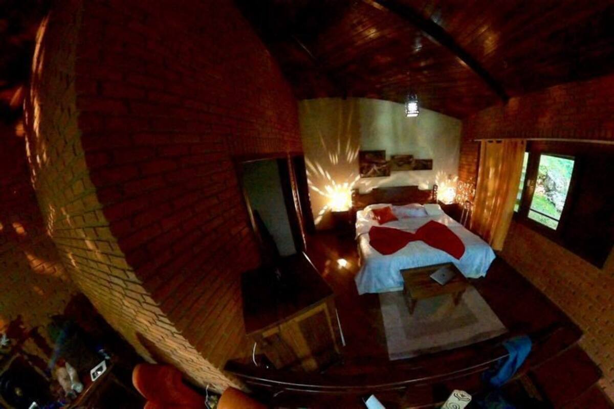 Een kamer met een bed, een raam en een houten plafond.