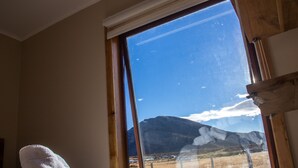 Ein Zimmer mit großem Fenster und Blick auf einen Berg und ein Feld.