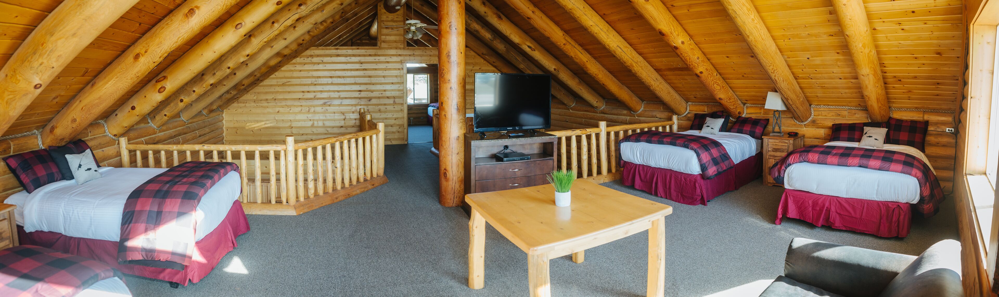 Una cabaña acogedora con habitación en el altillo, un televisor y una pequeña mesa.