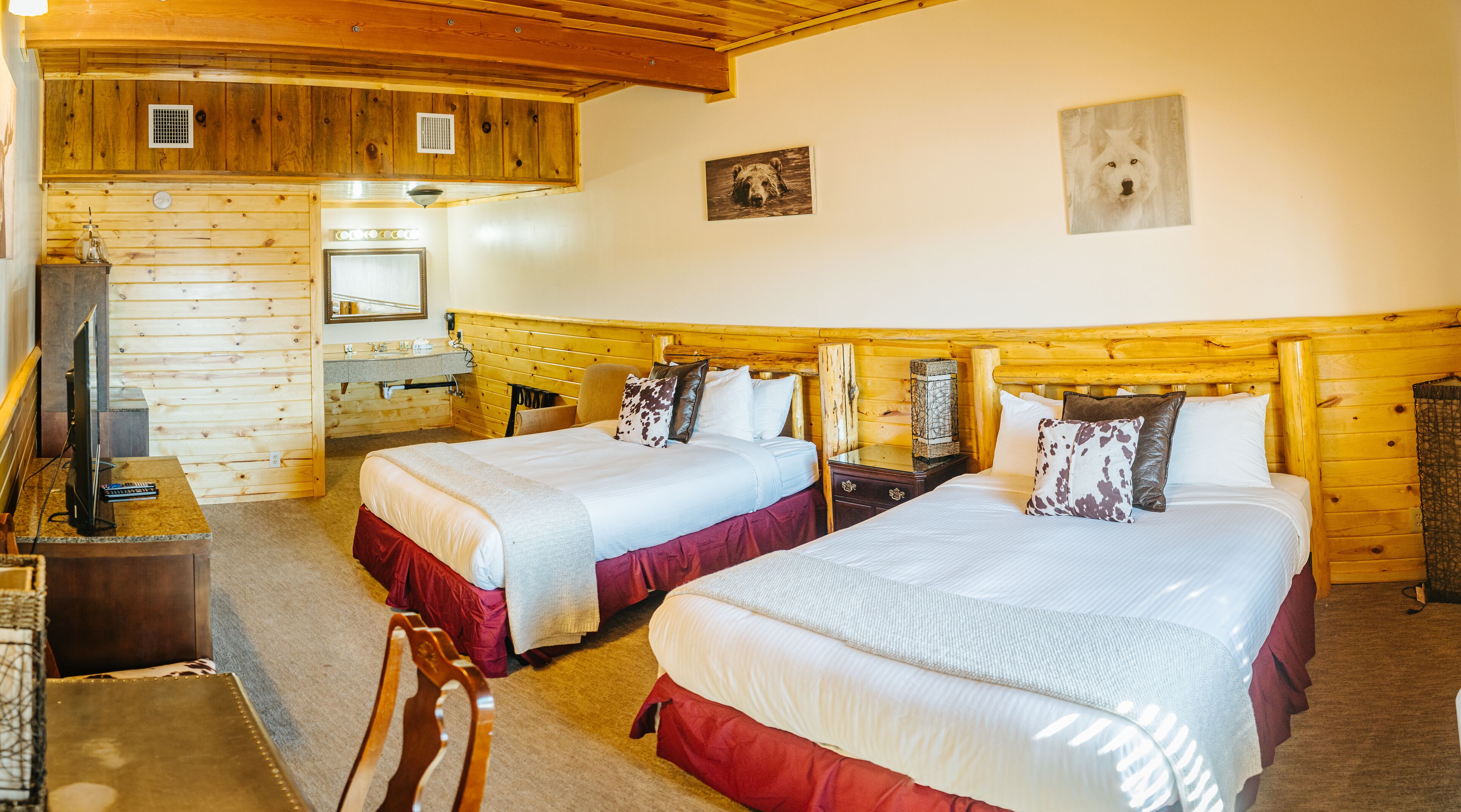 Une pièce aménagée comme un chalet en bois, avec deux lits, une télévision et un petit bureau.