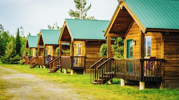 Cabins feature a front porch with stairs leading up to the entrance.