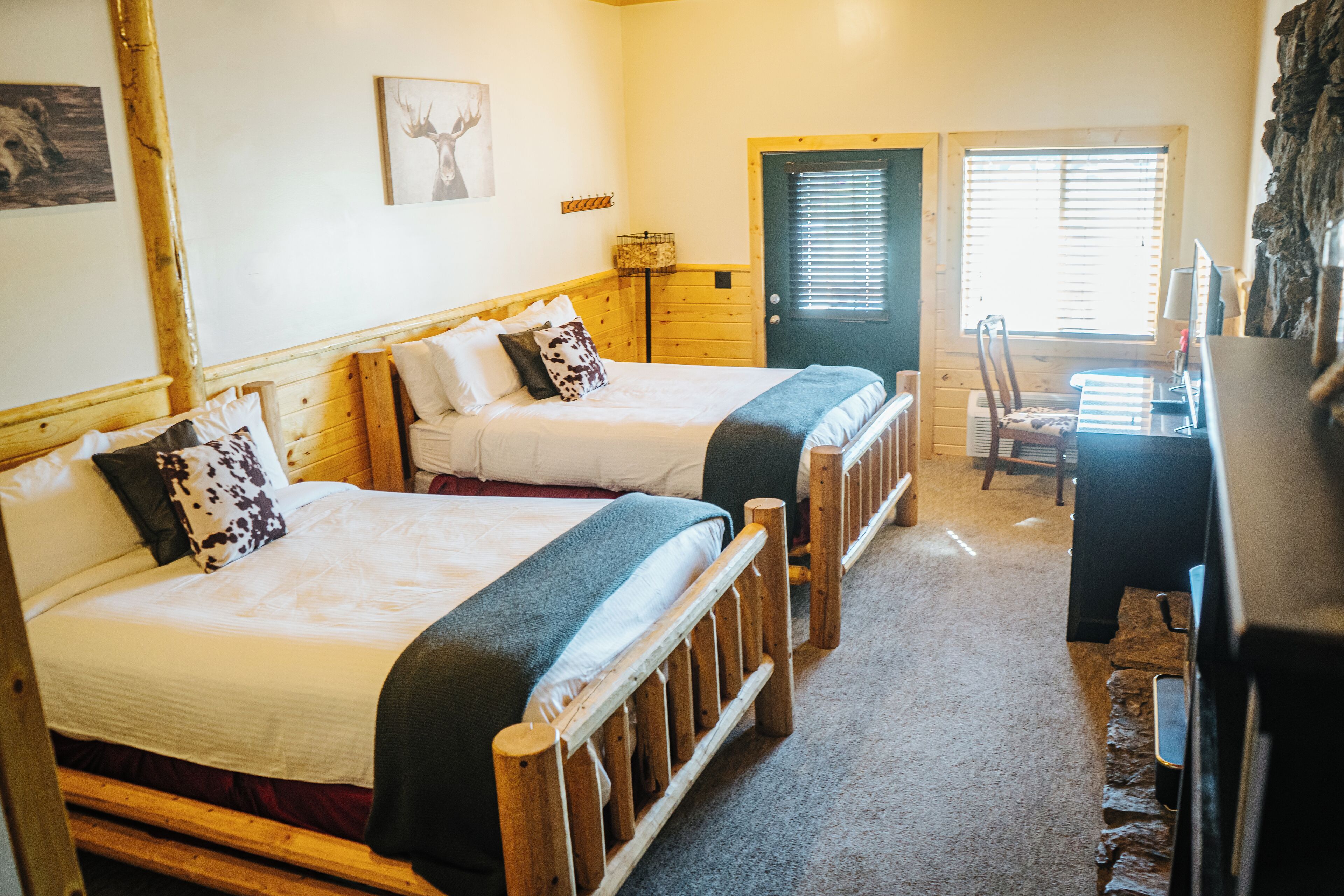 A room with two wooden beds, a desk, and a chair.