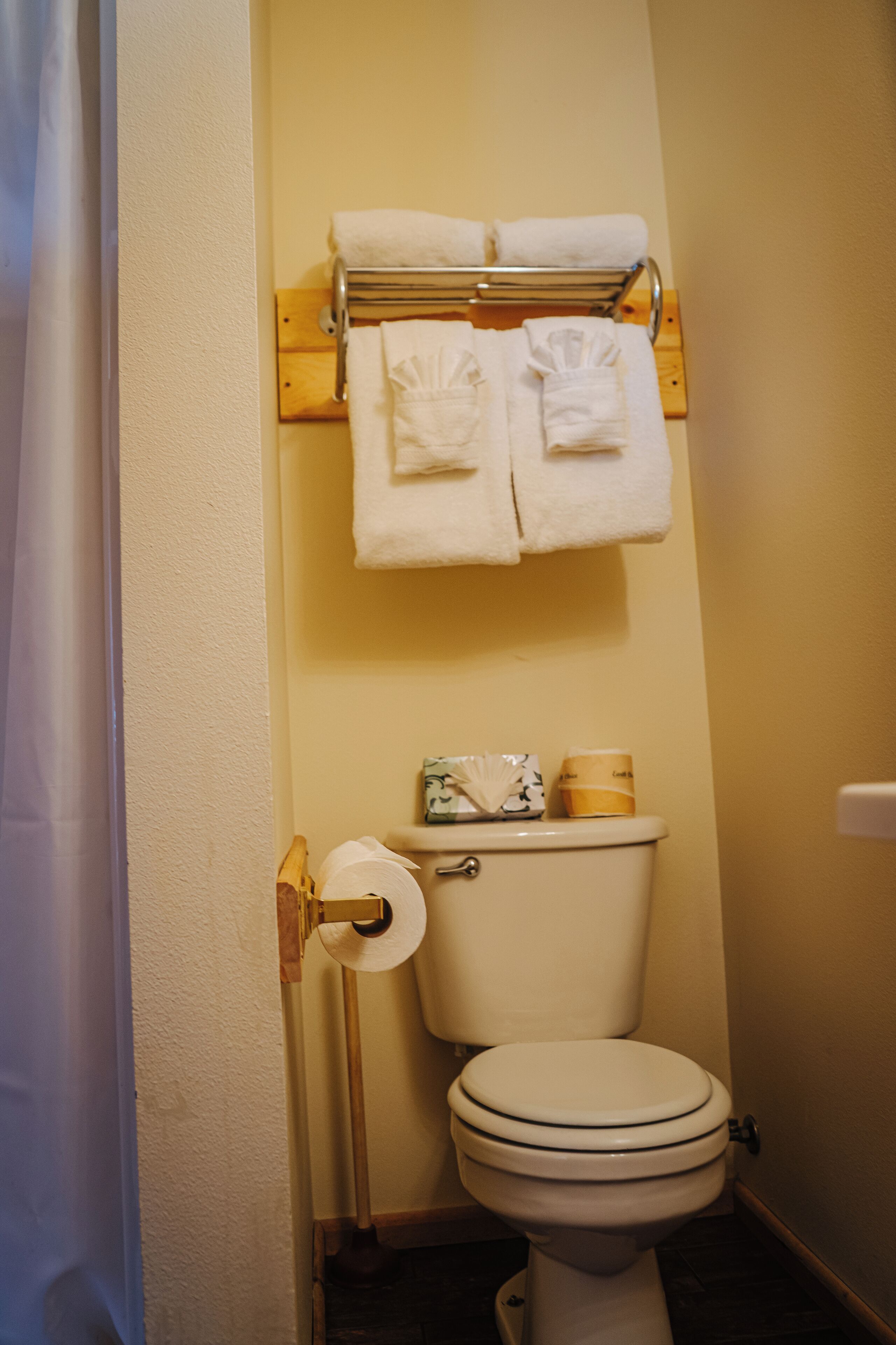 Ein Badezimmer mit Toilette, Handtuchhalter mit Handtüchern und Toilettenpapier.