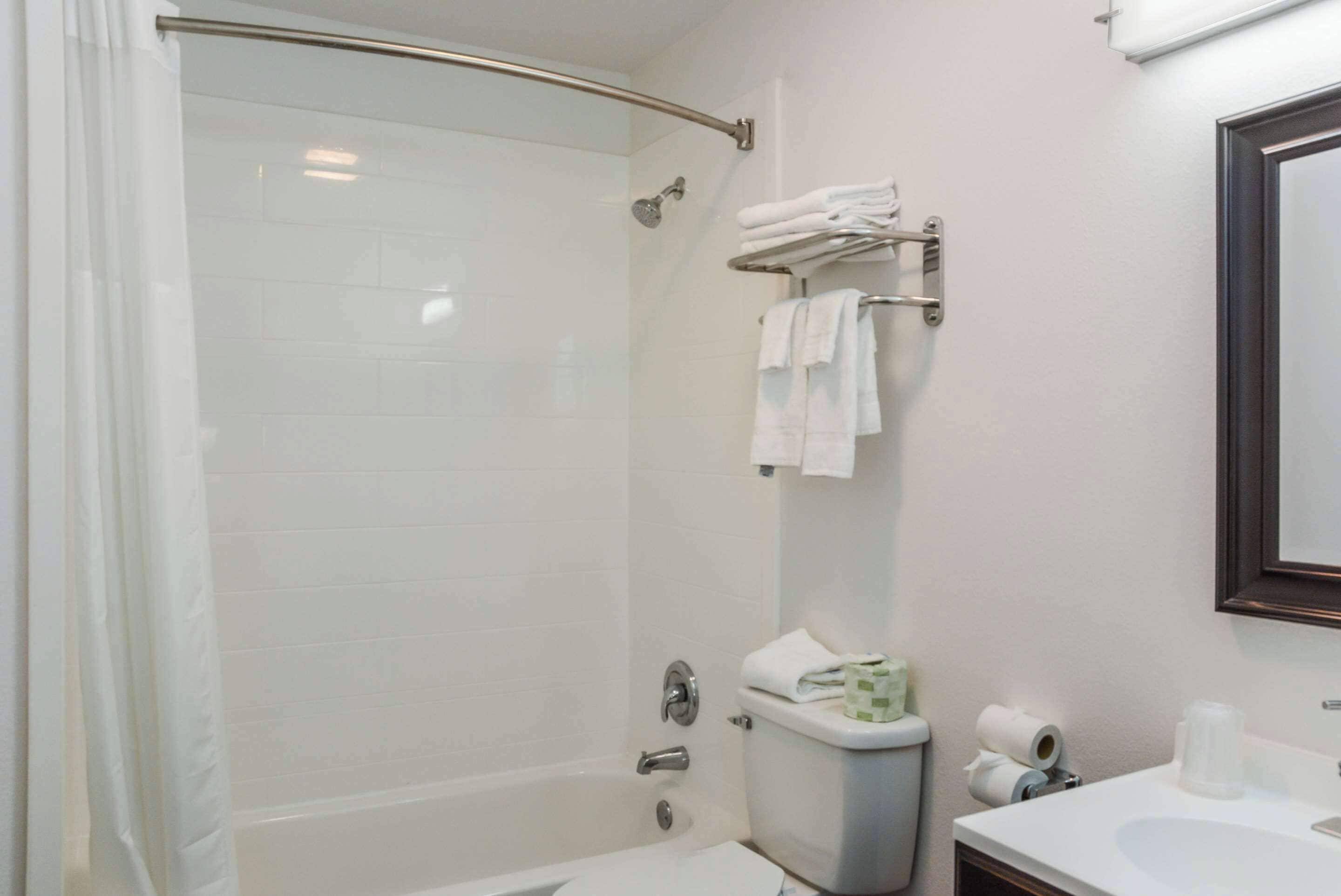 Un baño moderno con ducha de vidrio, inodoro y lavamanos con espejo.