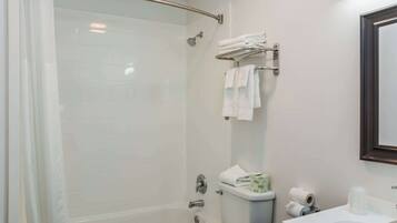 Un baño moderno con ducha de vidrio, inodoro y lavamanos con espejo.