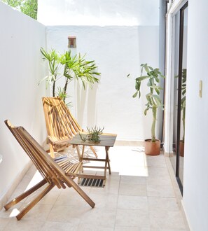 A small patio with a wooden chair, a table, and potted plants.