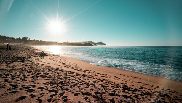 A beach with footprints in the sand, a clear sky, and the sun shining. - Scarlett Guesthouse Hotel Resorts (Bull Bay)