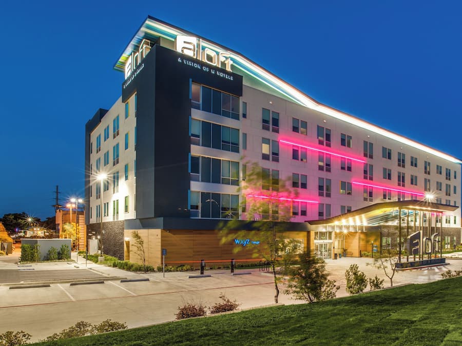 Un hotel moderno con un llamativo letrero de 'eLoft', un 'VixYZ lounge' y una entrada bien iluminada.