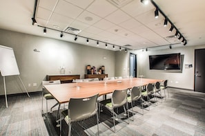 A conference room with a long table, chairs, a whiteboard, and a television screen on the wall. - Aloft by Marriott Dallas Arlington Entertainment District (Arlington)