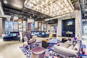A modern lounge area with seating, a coffee table, and a patterned rug. - Aloft by Marriott Dallas Arlington Entertainment District (Arlington)