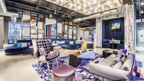 A modern lounge area with sofas, a coffee table, and a patterned rug. - Aloft by Marriott Dallas Arlington Entertainment District (Arlington)