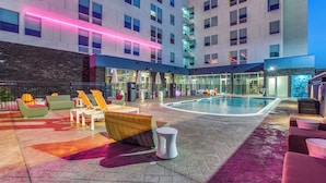 A hotel courtyard with a swimming pool, lounge chairs, and a bar area. - Aloft by Marriott Dallas Arlington Entertainment District (Arlington)