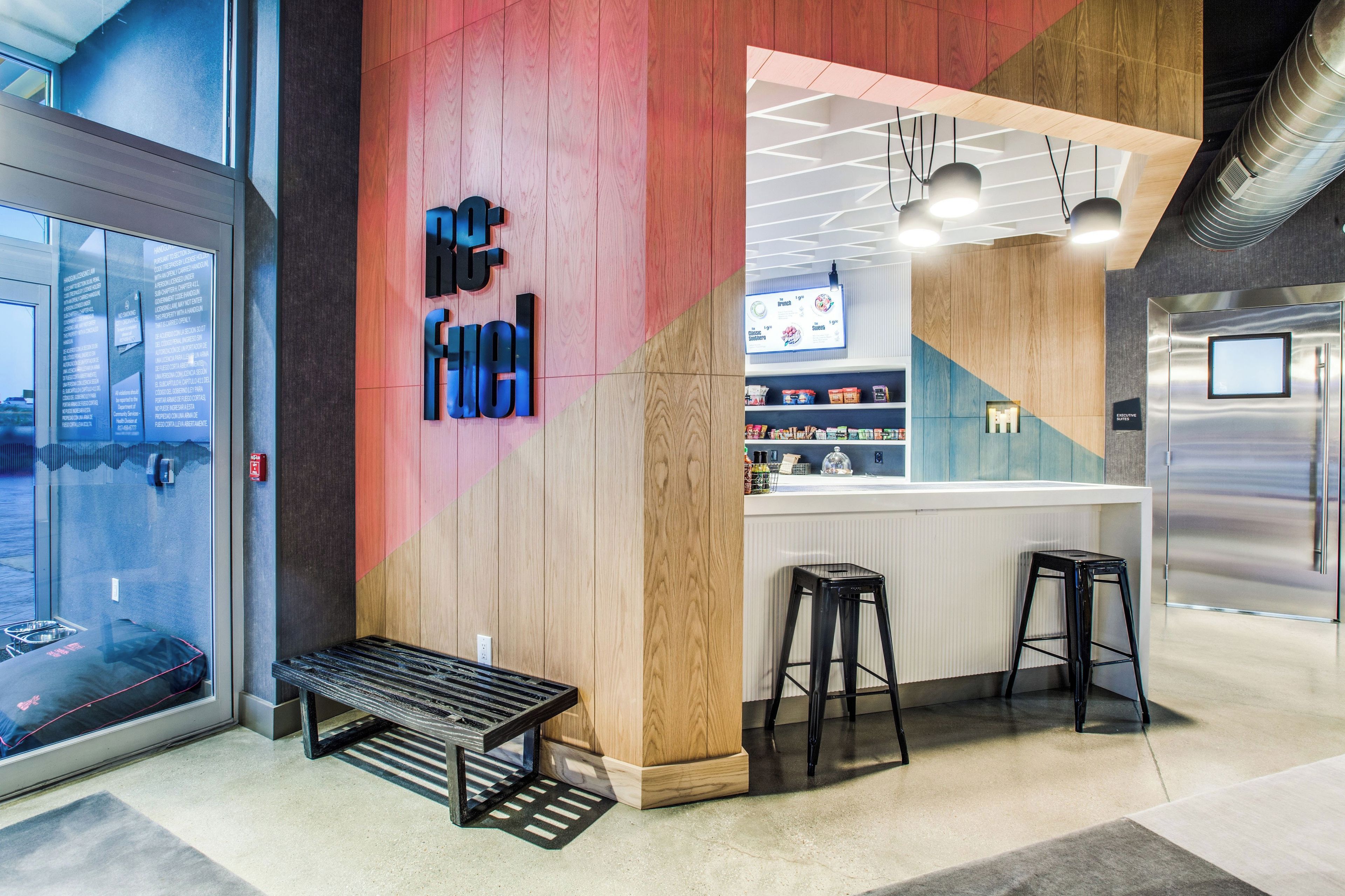 A modern interior with a wooden accent wall, a bar area with stools, and a glass partition.