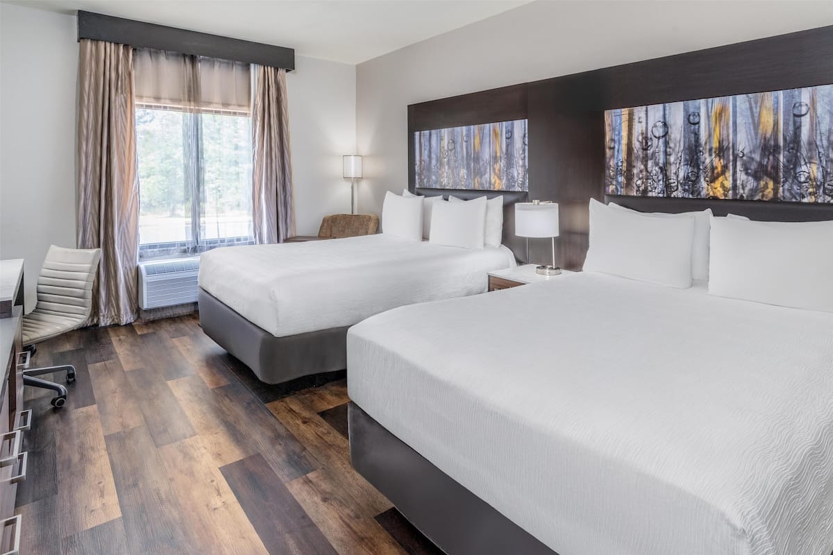 Ein Hotelzimmer mit zwei Betten, einem Schreibtisch und einem Stuhl.