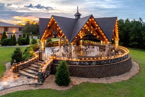 A circular outdoor patio with stone walls and wooden beams, surrounded by a stone walkway and steps leading to a covered seating area. - Aiden by Best Western Warm Springs Hotel and Event Center (Warm Springs)