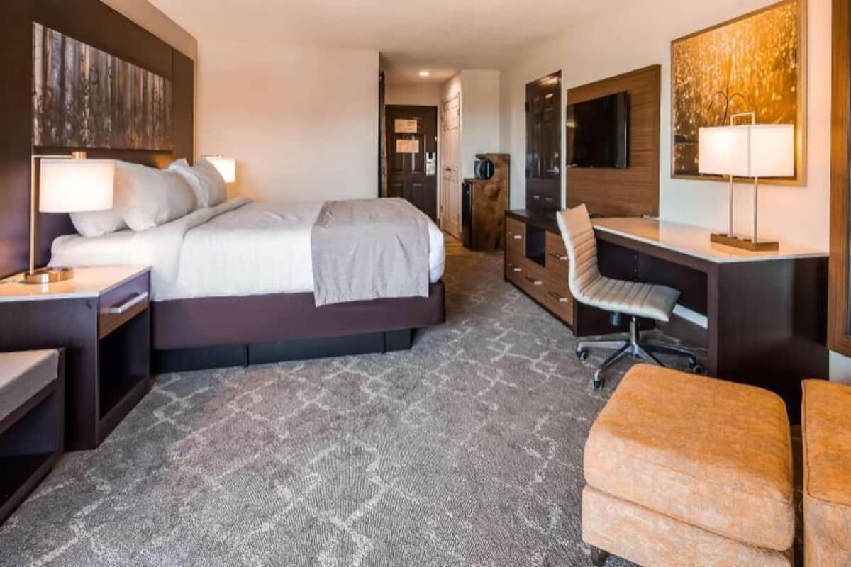Ein Hotelzimmer mit Bett, Schreibtisch, Stuhl und einem großen Spiegel.