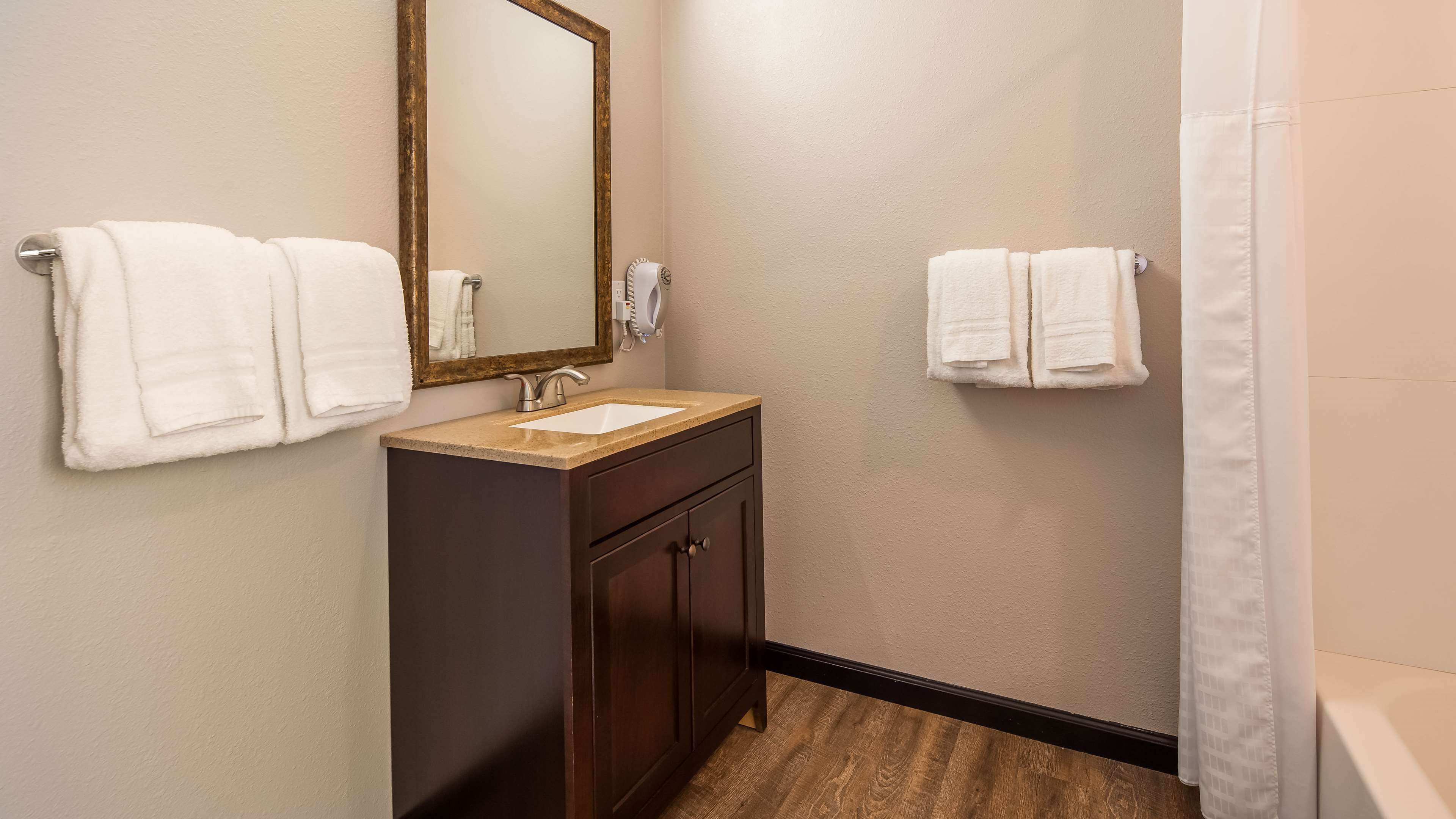 A bathroom with a sink, mirror, and two towels hanging on the wall.